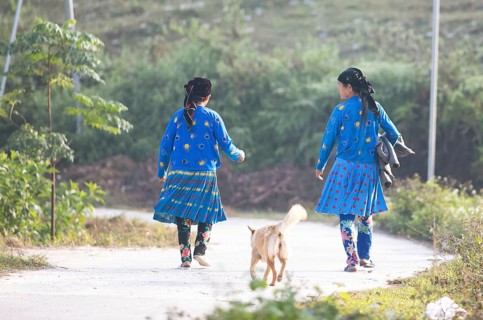 Two Hmong minority woman walk in everyday clothes on a street, Du Gia, Ha Giang province, Vietnam,