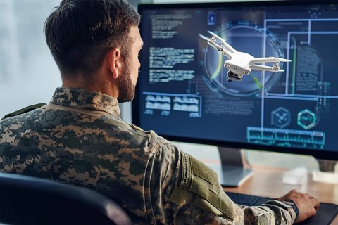 A soldier monitors and controls a drone via a digital user interface on a large screen, AI