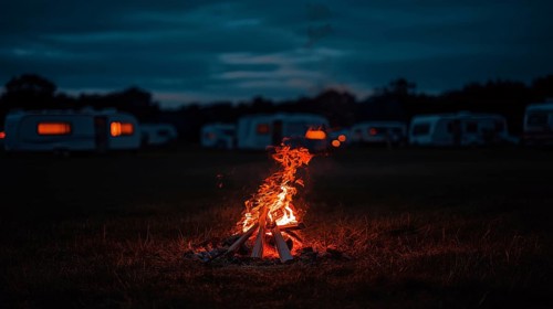 A campsite with caravans at night, featuring a central campfire emitting a warm glow, AI generated