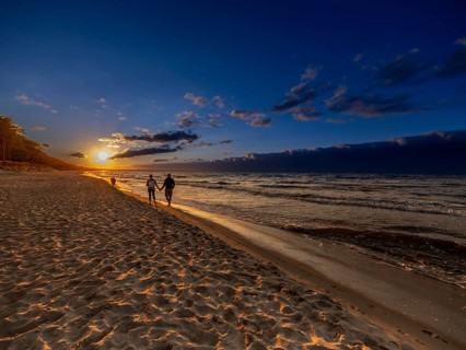A couple holding hands at sunset on the sandy beach on the island of Usedom on the Baltic Sea,