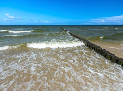 Sandy beach beach with wooden groyne in the Baltic Sea on the island of Usedom, clouds in the blue