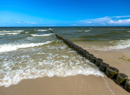 Sandy beach beach with wooden groyne in the Baltic Sea on the island of Usedom, clouds in the blue
