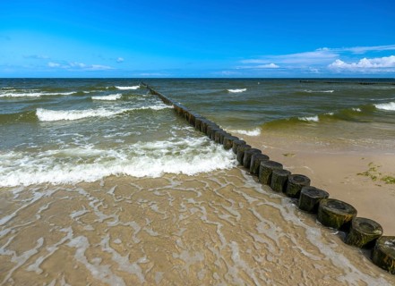 Sandy beach beach with wooden groyne in the Baltic Sea on the island of Usedom, clouds in the blue