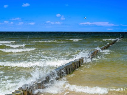 Spray splashes on a wooden groyne on a sandy beach on the Baltic Sea on the island of Usedom,