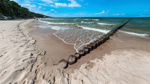 Sandy beach beach with wooden groyne in the Baltic Sea on the island of Usedom, clouds in the blue