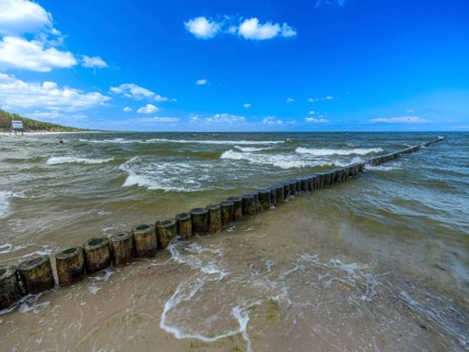 Sandy beach beach with wooden groyne in the Baltic Sea on the island of Usedom, clouds in the blue