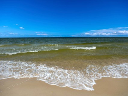 Water flowing onto the sandy beach on the island of Usedom on the Baltic Sea under a blue sky with