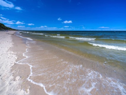 Water flowing onto the sandy beach on the island of Usedom on the Baltic Sea under a blue sky with