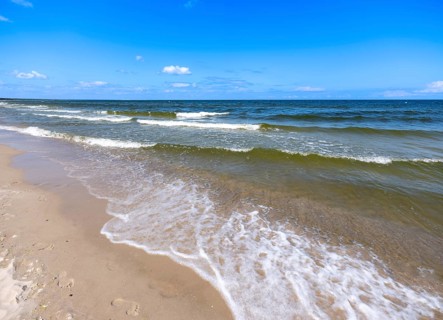Water flowing onto the sandy beach on the island of Usedom on the Baltic Sea under a blue sky with