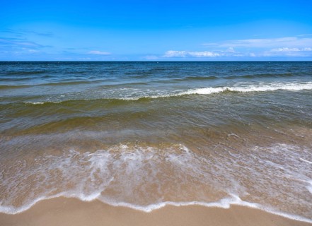 Water flowing onto the sandy beach on the island of Usedom on the Baltic Sea under a blue sky with