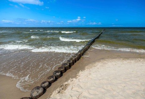 Sandy beach beach with wooden groyne in the Baltic Sea on the island of Usedom, clouds in the blue