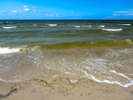 Water flowing onto the sandy beach on the island of Usedom on the Baltic Sea under a blue sky with