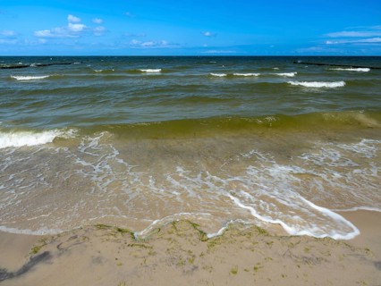 Water flowing onto the sandy beach on the island of Usedom on the Baltic Sea under a blue sky with