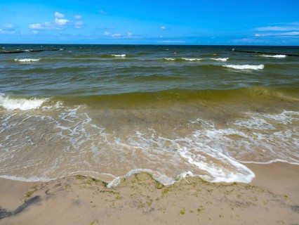 Water flowing onto the sandy beach on the island of Usedom on the Baltic Sea under a blue sky with
