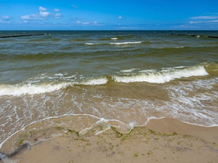 Water flowing onto the sandy beach on the island of Usedom on the Baltic Sea under a blue sky with