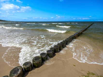 Sandy beach beach with wooden groyne in the Baltic Sea on the island of Usedom, clouds in the blue