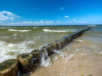 Spray splashes on a wooden groyne on a sandy beach on the Baltic Sea on the island of Usedom,