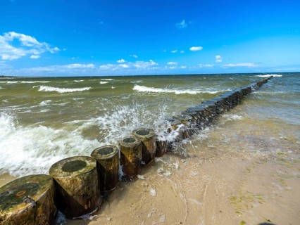 Spray splashes on a wooden groyne on a sandy beach on the Baltic Sea on the island of Usedom,