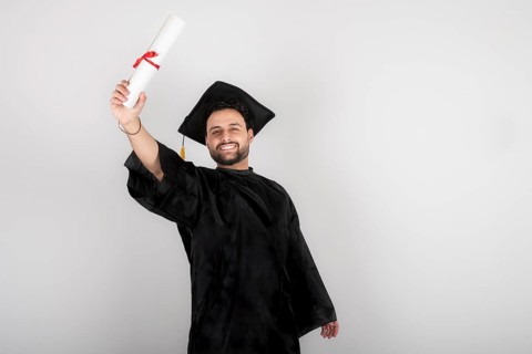 Recent graduate man, dressed in cap and gown, showing off his degree