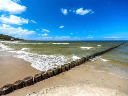 Sandy beach beach with wooden groyne in the Baltic Sea on the island of Usedom, clouds in the blue
