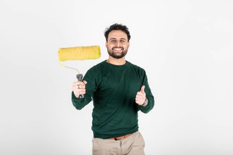 Smiling man holding a paint roller and giving thumbs up