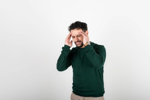 Stressed and tired man touches his head because of a headache