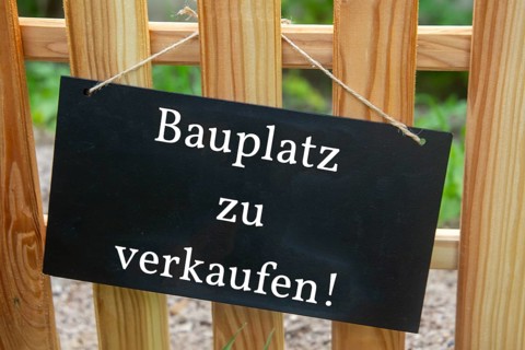Sign with the inscription BAUPLATZ ZU VERKAUFEN on a wooden fence (symbolic image)