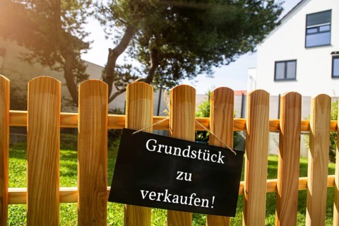 Sign with the inscription GRUNDSTÜCK ZU VERKAUFEN on a wooden fence (symbolic image)