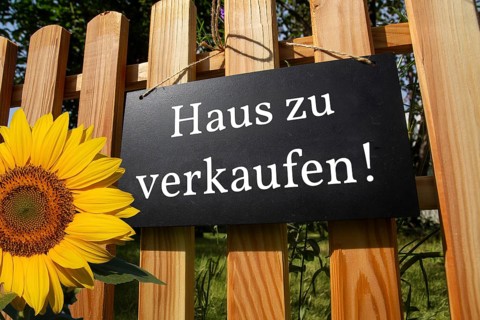 Sign with the inscription HAUS ZU VERKAUFEN on a wooden fence (symbolic image)