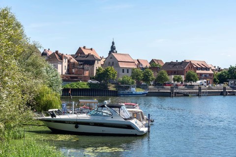 A boat is anchored, behind it parts of the old town centre of Havelberg, Saxony-Anhalt, Germany,