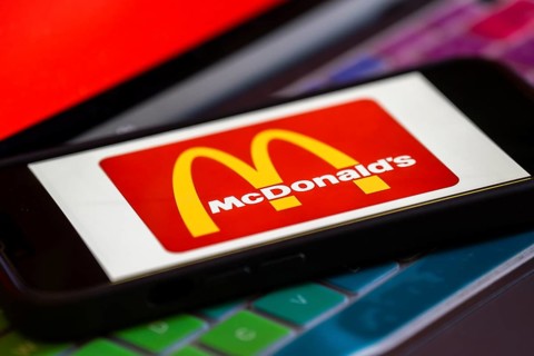 In this photo illustration, McDonald's logo is displayed on a smartphone with a laptop display