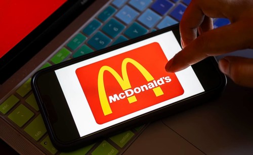 In this photo illustration, McDonald's logo is displayed on a smartphone with a laptop display