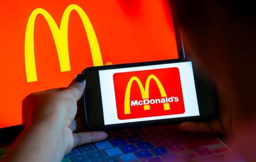 In this photo illustration, McDonald's logo is displayed on a smartphone with a laptop display