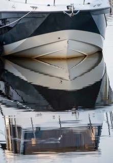 The bow of a ship is reflected in the Tanger river at the harbour at the mouth of the Elbe,