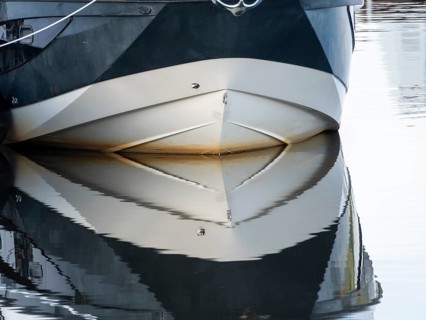 The bow of a ship is reflected in the Tanger river at the harbour at the mouth of the Elbe,