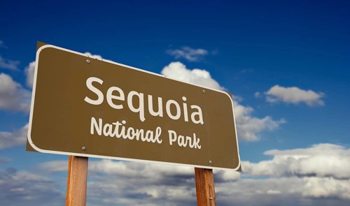 Sequoia national park (california) road sign against blue sky and clouds