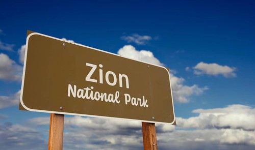 Zion national park (utah) road sign against blue sky and clouds