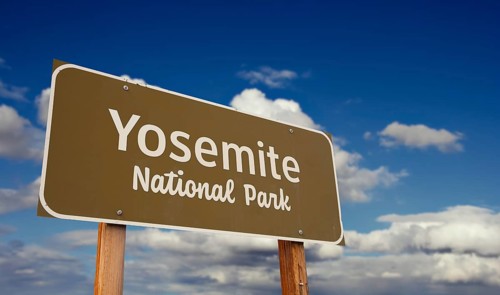 Yosemite national park (california) road sign against blue sky and clouds
