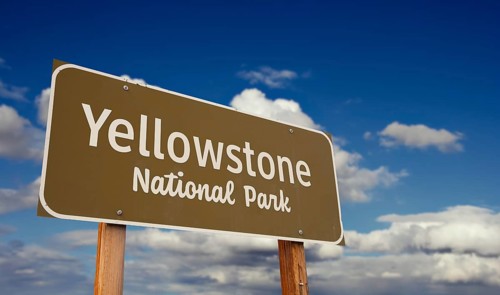 Yellowstone national park (wyoming, montana, idaho) road sign against blue sky and clouds
