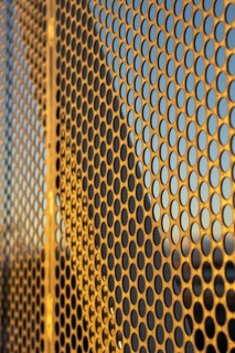 Aluminum composite panels or cladding with perforated sheets on modern building facade on sunset,