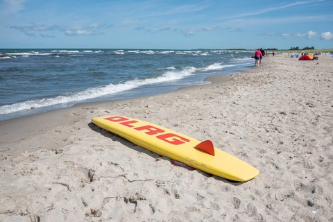 A rescue board of the German Life Saving Association DLRG lies on the sandy beach of the Baltic