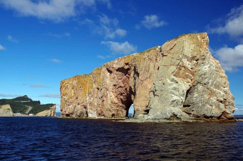 Large rocky cliffs in the sea under a blue sunny sky, Rock of Perce, Perce, St. Lawrence River,