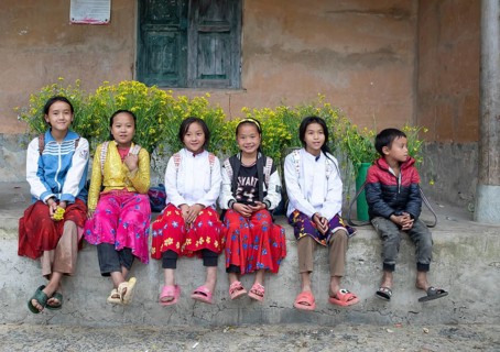 Vietnamese girls with baskets of flowers on their backs sitting on a ledge, Lungcam Cultural