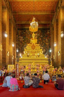 Worshippers oin front of Phra Buddha statue at the Phra Ubosot ordination hall, Wat Pho complex,