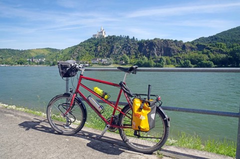 A bicycle stands in front of a railing with a view of the river and a castle on a hill, Middle