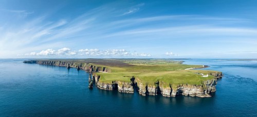 Aerial panorama of the rugged coastal landscape at Duncansby Head with the lighthouse on the right,