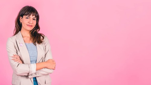 Smiling woman wearing a pink breast cancer awareness ribbon on her coat. Copy space