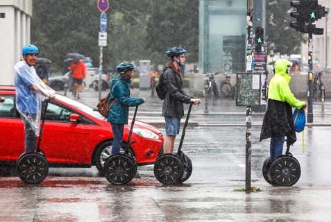 Tourists standing at a traffic light in heavy rain with Segway personal transporters, Berlin, 23 06