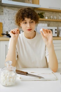 Brave woman looks at a piece of sugar wanting to reduce the amount of sweets in her food