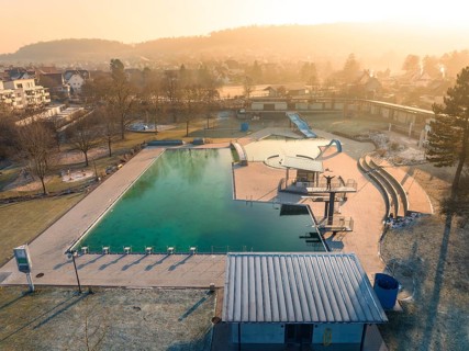View of a swimming pool with slides and nearby residential buildings in the morning sun and frozen